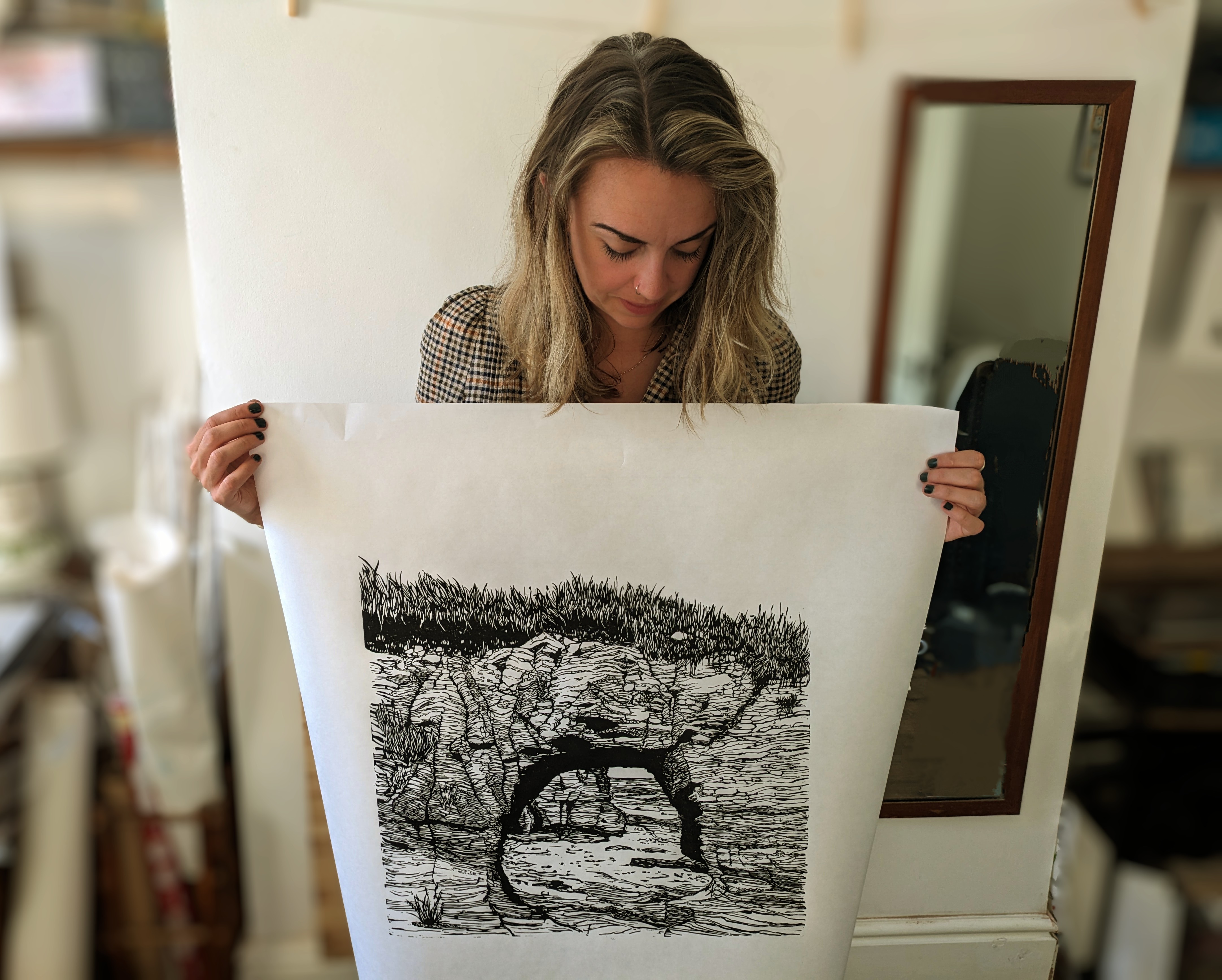 Jess Evans holding linoprint of rock archway