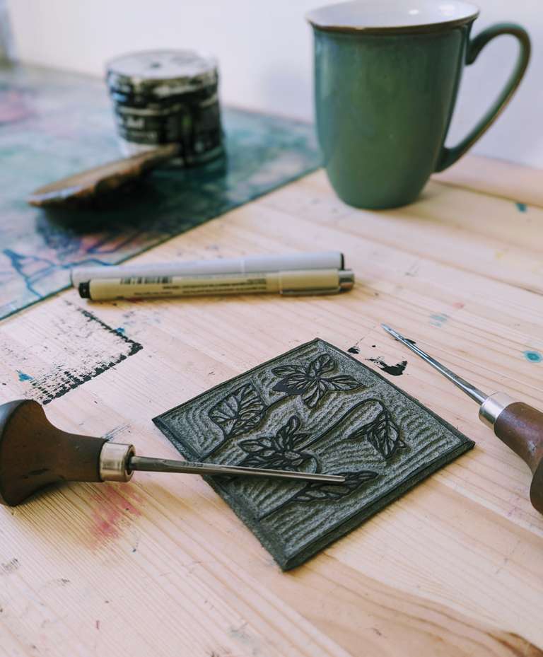 Lino block with a carving tool and cup of tea