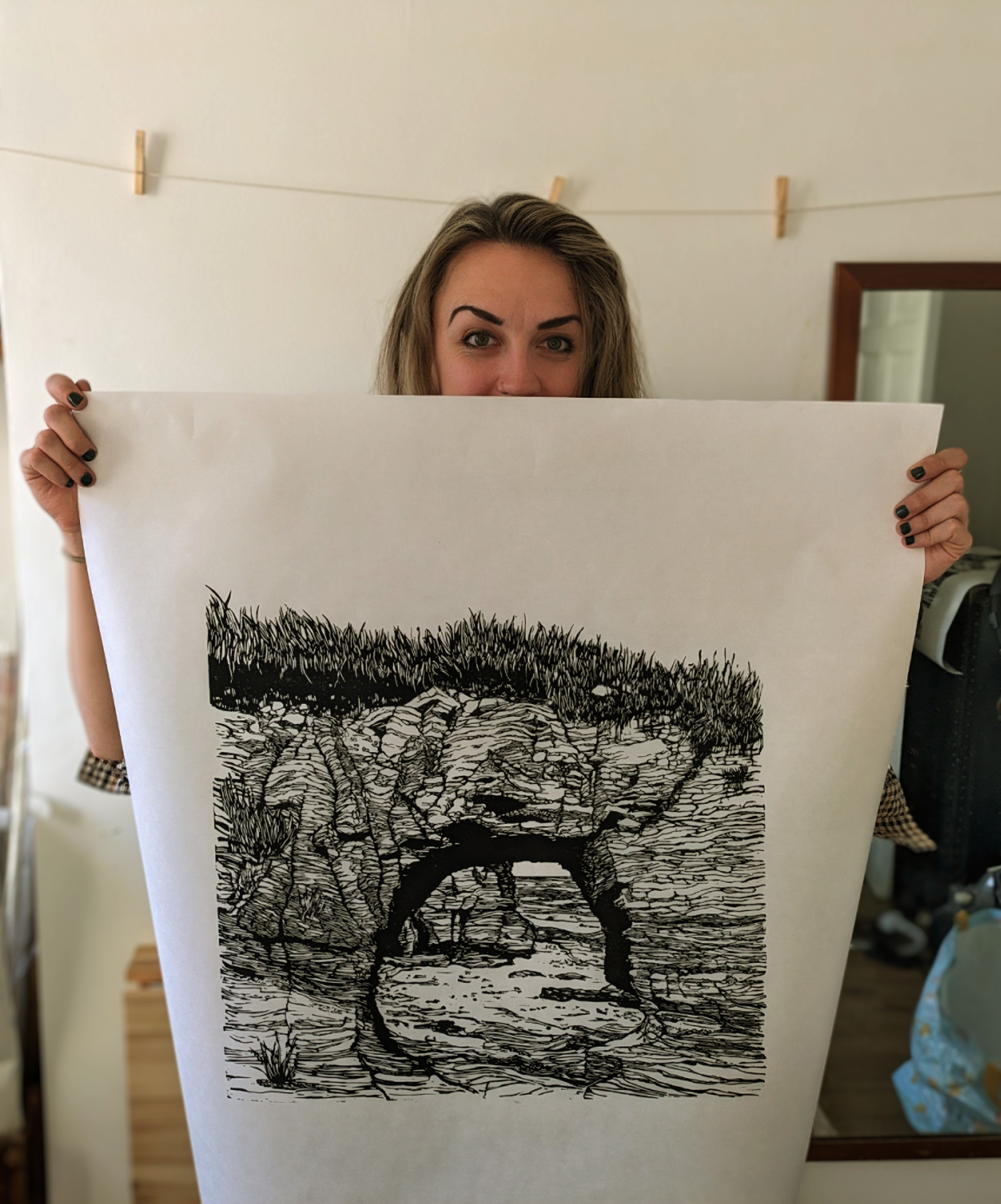 Jessie Evans holding a linoprint of a rock arch